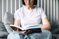 Young woman reading book on bed at home. Concept of cozy, comfort home. Lifestyle, authentic moment Royalty Free Stock Photo