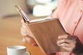 Young woman reading book in cafe, closeup