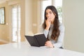 Young woman reading a book cover mouth with hand shocked with shame for mistake, expression of fear, scared in silence, secret