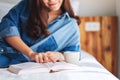 A young woman reading book and drinking hot coffee in a white cozy bed at home Royalty Free Stock Photo