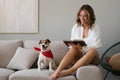 Young woman reading book and her cute dog on sofa at home. Lovely pet. Royalty Free Stock Photo