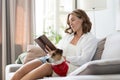 Young woman reading book and her cute dog on sofa at home. Lovely pet. Royalty Free Stock Photo