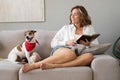 Young woman reading book and her cute dog on sofa at home. Lovely pet. Royalty Free Stock Photo