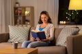 Young woman reading book at home in evening Royalty Free Stock Photo