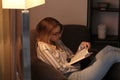 Young woman reading book at home in evening Royalty Free Stock Photo