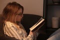 Young woman reading book at home in evening Royalty Free Stock Photo