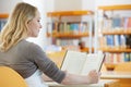 Young woman reading book in library