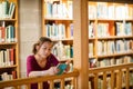 Young woman reading book in library Royalty Free Stock Photo