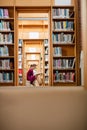 Young woman reading book in library Royalty Free Stock Photo