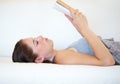 Reading her favorite novel. A young woman reading a book while lying on the couch. Royalty Free Stock Photo