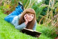 Young woman reading a book lying on the grass Royalty Free Stock Photo