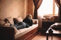 Young woman reading book while lying on sofa