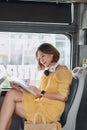 Young woman reading book while moving in the modern tram, happy passenger at the public transport