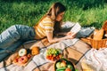 Young woman reading book outdoors, in natural park on picnic, lying on a picnic blanket and enjoying summer weather Royalty Free Stock Photo