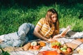 Young woman reading book outdoors, in natural park on picnic, lying on a picnic blanket and enjoying summer weather Royalty Free Stock Photo