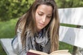 Young woman reading a book on a park bench Royalty Free Stock Photo