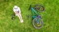 Young woman reading book in park near bike. Student girl relaxing outdoors sitting on grass with bicycle, book and headphones Royalty Free Stock Photo