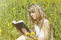 Young woman reading a book on the meadow Royalty Free Stock Photo