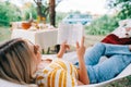 Young woman reading book, relaxing in hammock outdoors, in the backyard garden Royalty Free Stock Photo