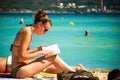 Young woman reading a book at sandy beach. People sunbathing at Playa de Muro. Mallorca island famous Royalty Free Stock Photo