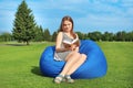 Young woman reading book while sitting on bean bag chair outdoors Royalty Free Stock Photo