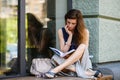 Young woman reading a book while sitting on a windowsill outdoors Royalty Free Stock Photo