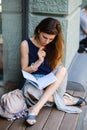 Young woman reading a book while sitting on a windowsill outdoors Royalty Free Stock Photo