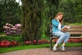 Young woman reading book while sitting on wooden bench in park Royalty Free Stock Photo