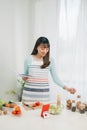 Young woman reading cookbook in the kitchen, looking for recipe Royalty Free Stock Photo