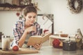 Young woman reading cookbook in the kitchen, looking for recipe Royalty Free Stock Photo