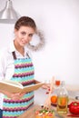 Young woman reading cookbook in the kitchen, looking for recipe Royalty Free Stock Photo