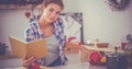 Young woman reading cookbook in the kitchen, looking for recipe Royalty Free Stock Photo