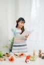 Young woman reading cookbook in the kitchen, looking for recipe Royalty Free Stock Photo