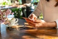 Young woman reading good news on mobile phone during rest in coffee shop, happy Asian female watching her photo on smart phone Royalty Free Stock Photo