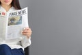 Young woman reading newspaper against grey background Royalty Free Stock Photo