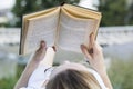 Young woman reading an old book lying outdoors at summer day Royalty Free Stock Photo