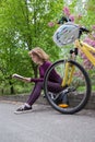 Young woman reads a book with interest, sitting next to a bicycle under a tree on a spring day in the park Royalty Free Stock Photo