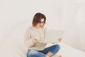 Young woman reads from laptop in bed, high key Royalty Free Stock Photo