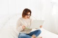 Young woman reads from laptop in bed, high key Royalty Free Stock Photo