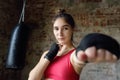 Young woman ready for hits punching bag during a boxing training. Female boxer doing fitness
