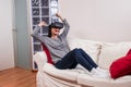 Young woman realxing on the couch and having fun playing a virtual reality simulation