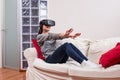 Young woman realxing on the couch and having fun playing a virtual reality simulation