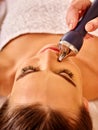 Young woman receiving electric facial massage.