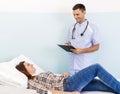 Young woman on reception at the doctor. Male doctor examining a patient. The workplace of the doctor at the clinic