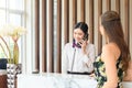 Young woman receptionist talking on the phone at workplace with female travellers standing at reception desk in hotel Royalty Free Stock Photo