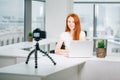 Young woman recording video on camera mounted on tripod for her vlog Royalty Free Stock Photo