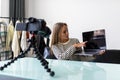 Young woman recording video for her vlog on a digital camera mounted on flexible tripod. Smiling woman sitting at her desk pointed Royalty Free Stock Photo