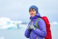 A young woman with a red backpack is standing against a background of blue icebergs. Ice lagoon in Iceland Royalty Free Stock Photo