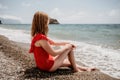 Young woman in red bikini on Beach. Blonde in sunglasses on pebble beach enjoying sun. Happy lady in one piece red Royalty Free Stock Photo