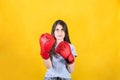 Young woman with red boxing gloves stands in fighting position. Portrait of determined girl prepared for battle isolated on yellow Royalty Free Stock Photo